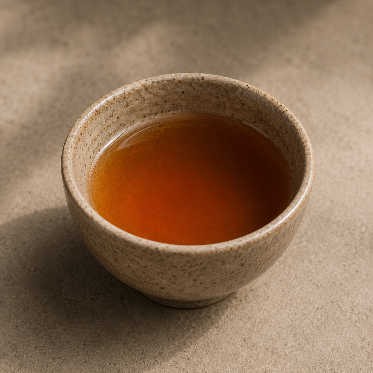 Freshly brewed Da Hong Pao Oolong tea in a small beige ceramic cup on a neutral surface.